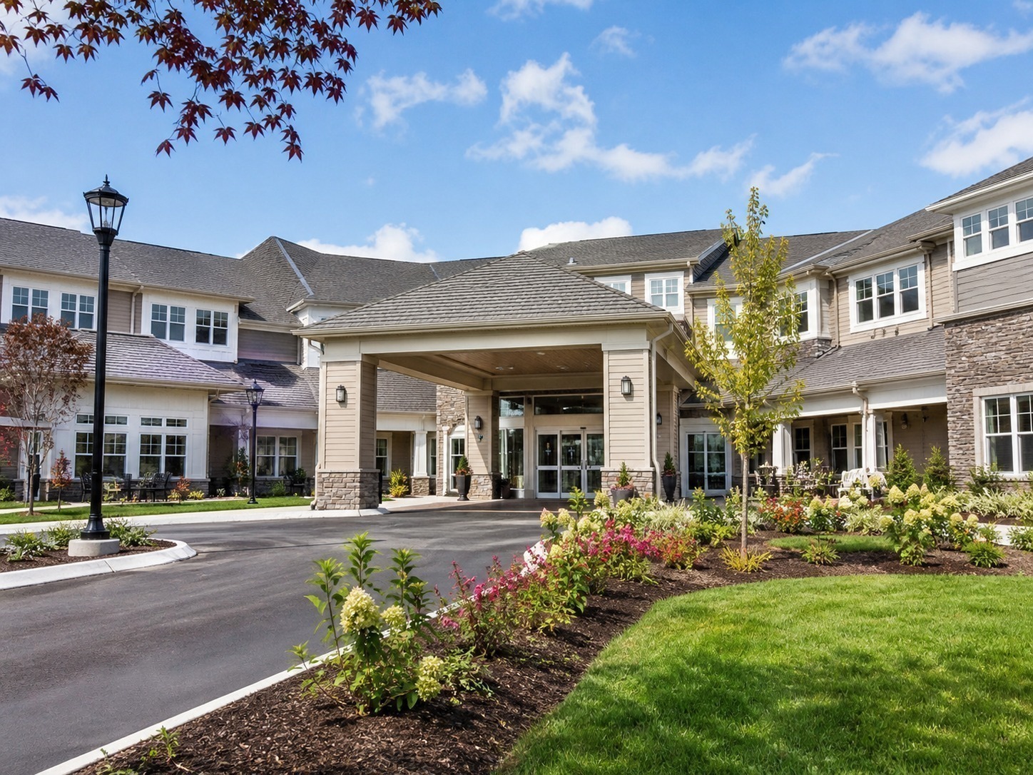 Senior living community exterior with families and caregivers entering the building